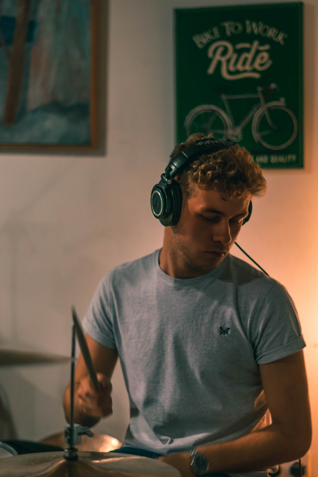 Mężczyzna w słuchawkach i w szarek koszulce gra na perkusji