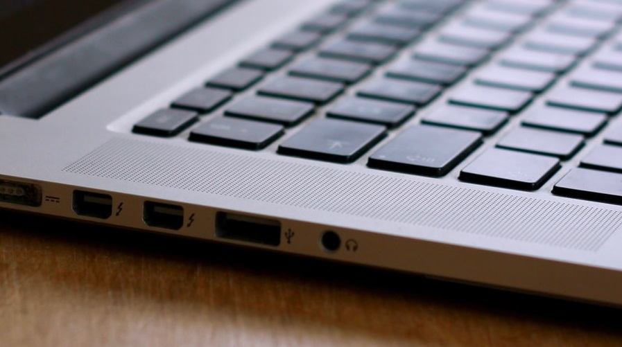 Fragment klawiatury srebrnego laptopa z portami USB, Thunderbolt i Mini Jack