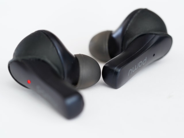 Bezprzewodowe czarne słuchawki douszne z logiem Pamu i czerwoną diodą na lewej słuchawce