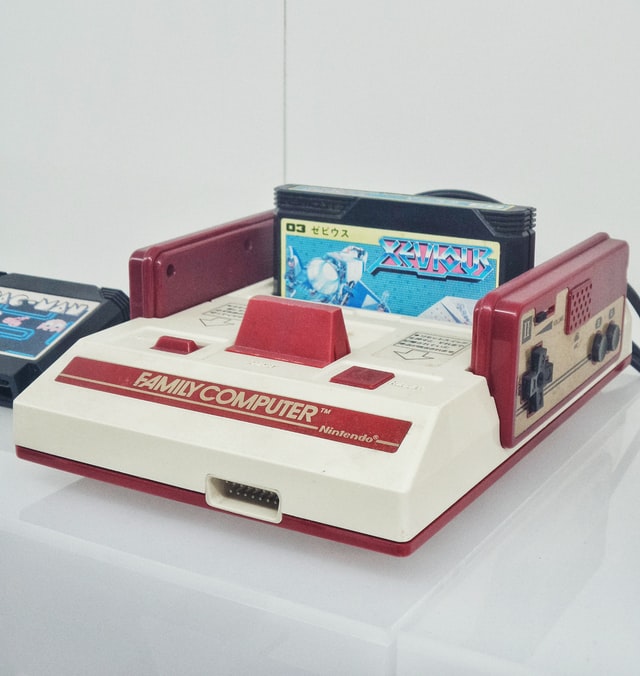 Biało-czerwony Nintendo Family Computer z umieszczoną czarną kasetą z grą