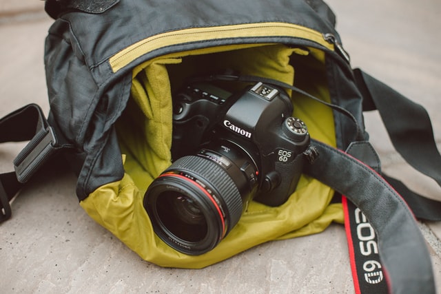 Ile kosztuje plecak na aparat fotograficzny? Czerny aparat sony wystający z leżącego żółto-czarnego plecaka